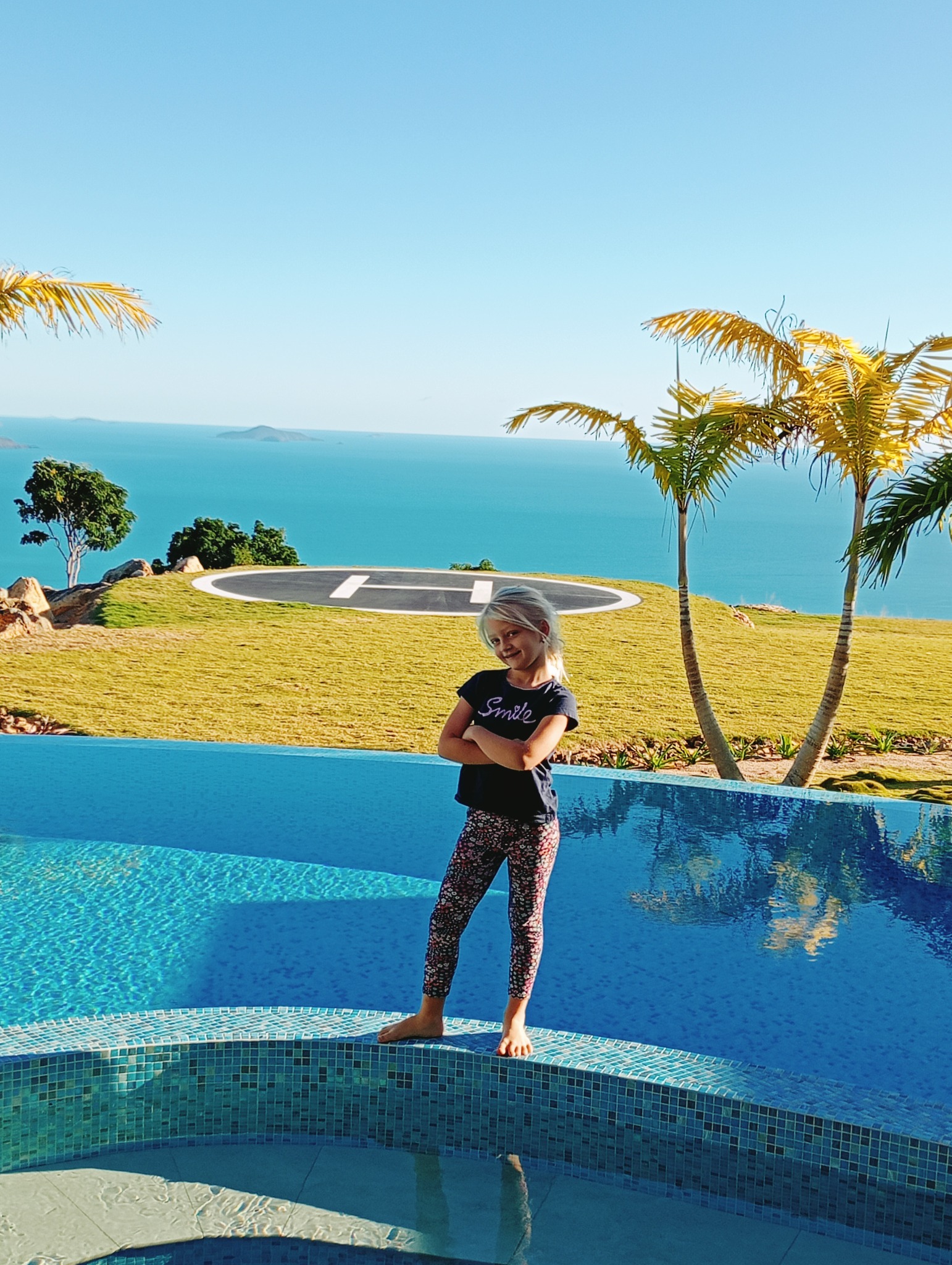 Young girl beside a sparkling Whitsundays pool with ocean views